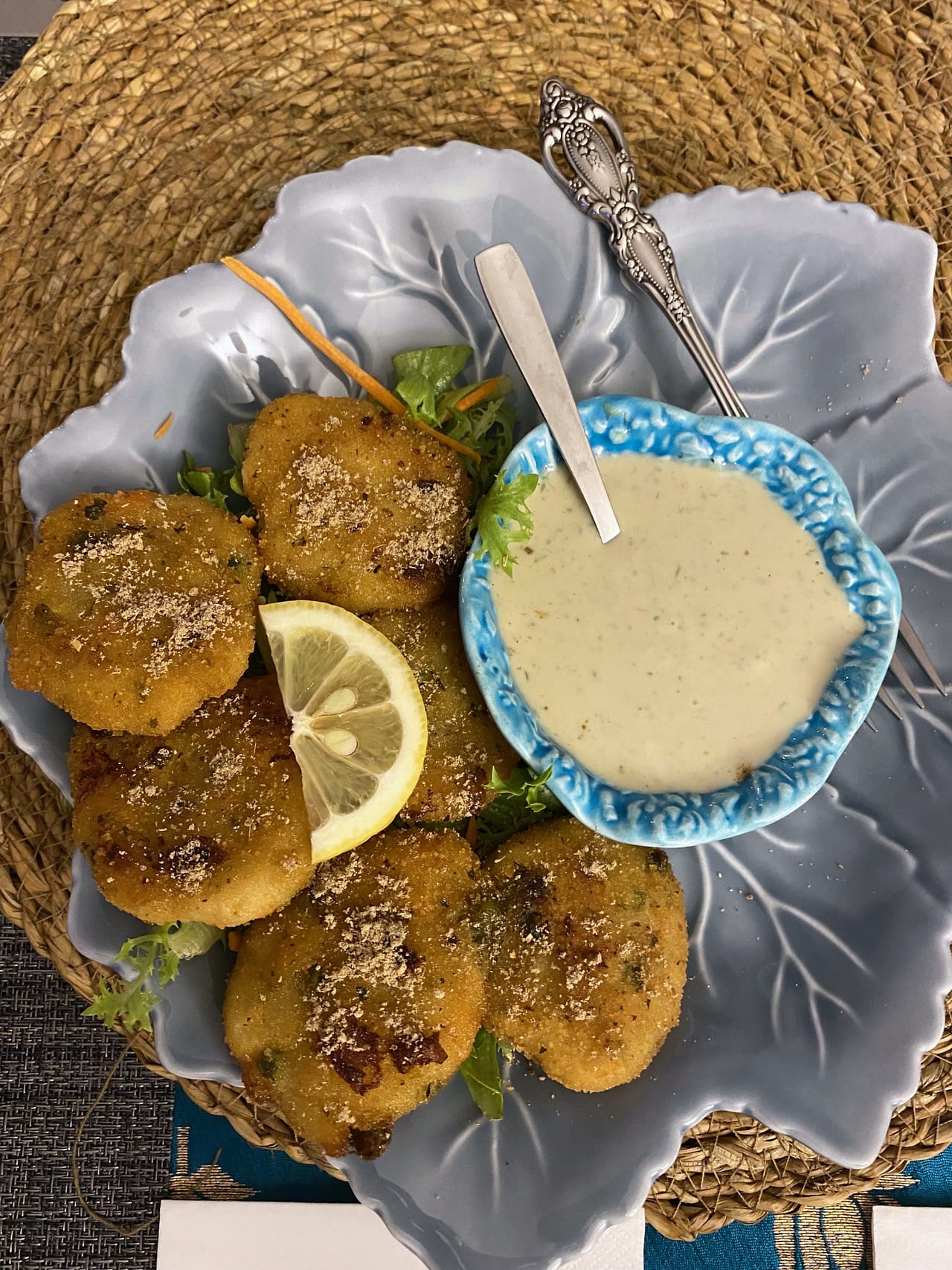 Seis pastéis fritos num prato cinzento ondulado, com alface, gomo de limão e uma taça azul de molho de iogurte